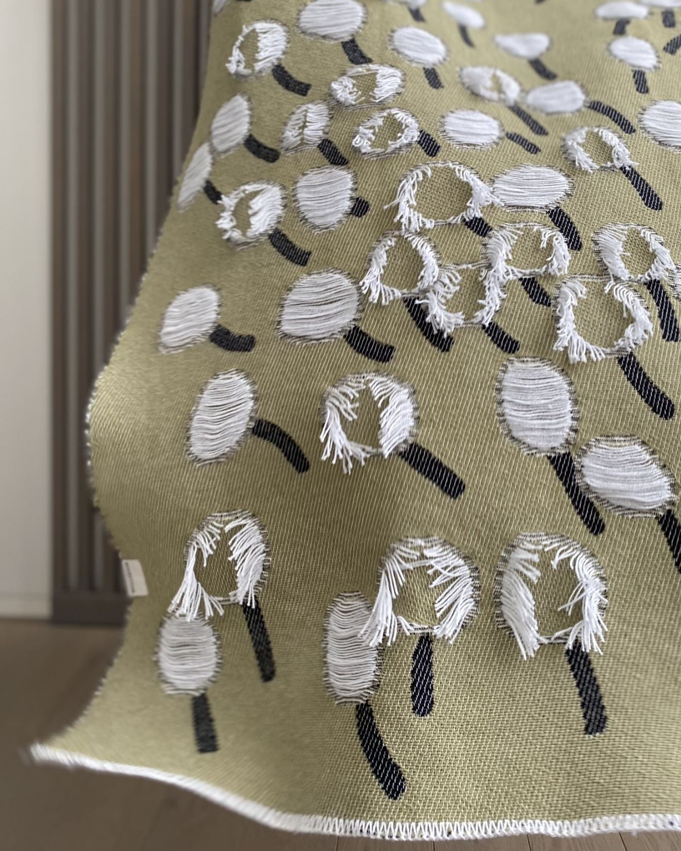 Olive green cotton blanket with dandelion pattern designed by Liucija Kostiva