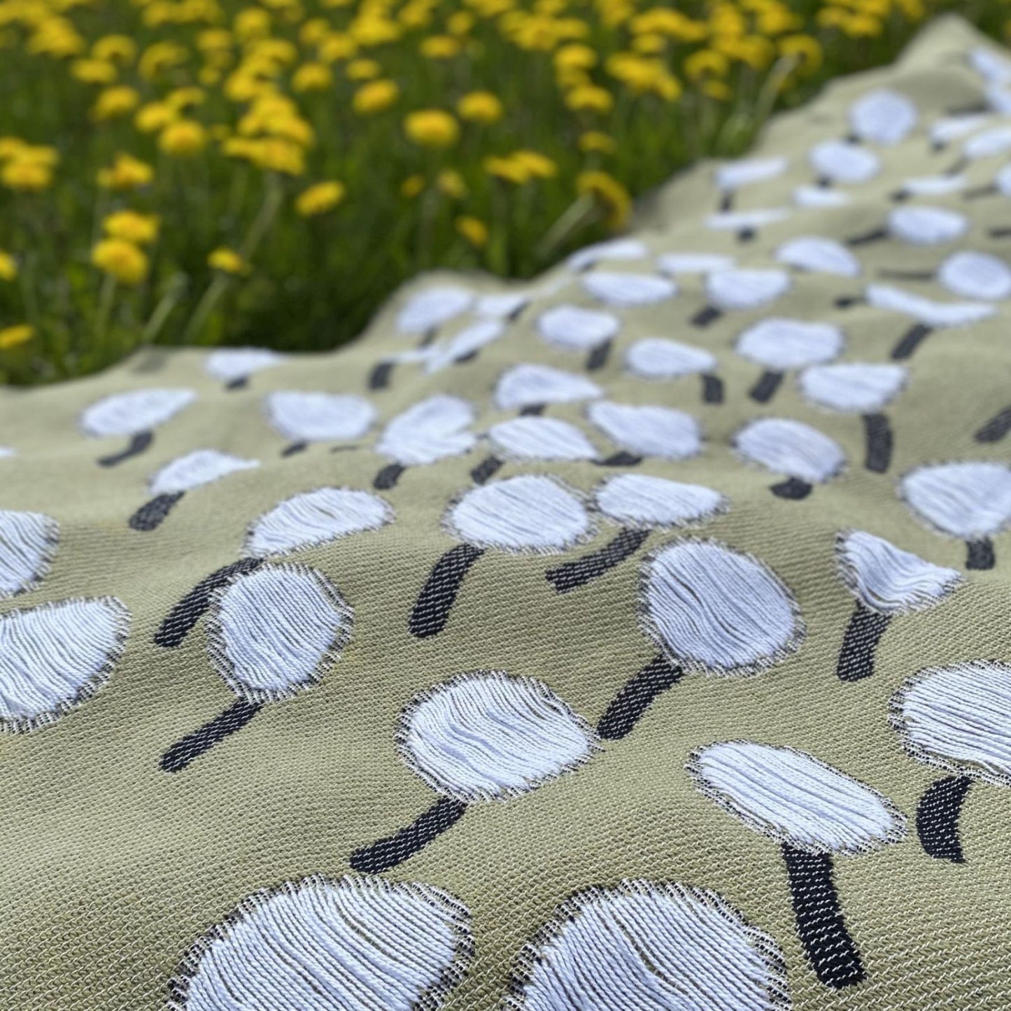 Closeup of cotton blanket with dandelion pattern designed by Liucija Kostiva