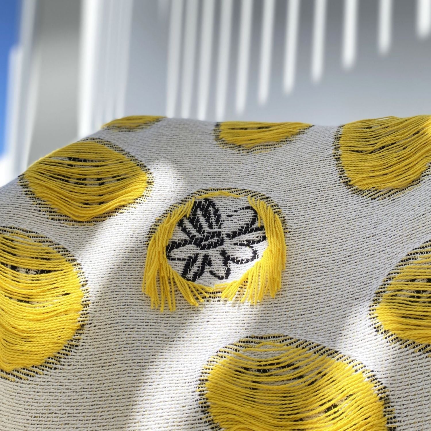 Closeup of yellow and white cotton blanket with daisies and fringes designed by Liucija Kostiva
