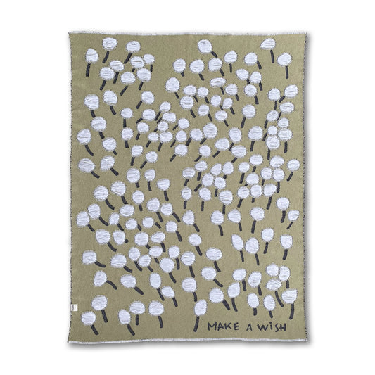 A cotton blanket with a dandelion design and the text 'Make a Wish' on a olive green background designed by Liucija Kostiva